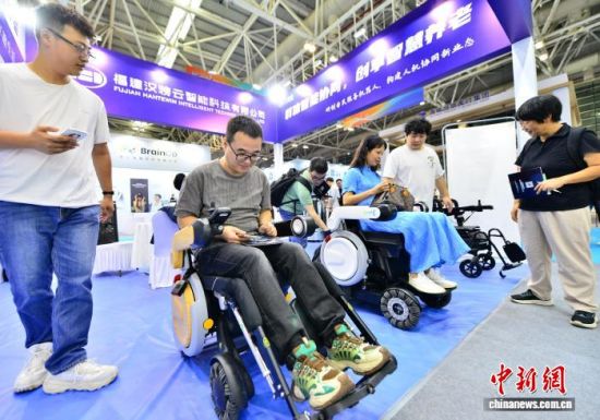 图为展馆内椅夫辅助康复运动机器人吸引参观者体验。中新社记者 张斌 摄 图为展馆内椅夫辅助康复运动机器人吸引参观者体验。中新社记者 张斌 摄