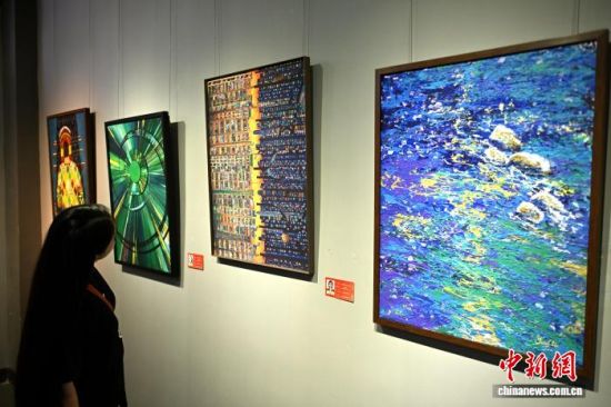 图为版画作品《光轴共栖》吸引参观者。中新社记者 吕明 摄 图为版画作品《光轴共栖》吸引参观者。中新社记者 吕明 摄