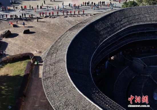 图为参赛选手从土楼旁经过。(无人机照片)中新社记者 张斌 摄 图为参赛选手从土楼旁经过。(无人机照片)中新社记者 张斌 摄