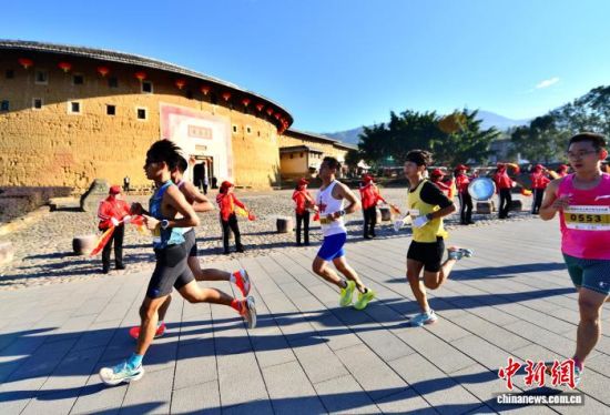图为参赛选手从“福建土楼王”承启楼前经过。中新社记者 张斌 摄 图为参赛选手从“福建土楼王”承启楼前经过。中新社记者 张斌 摄
