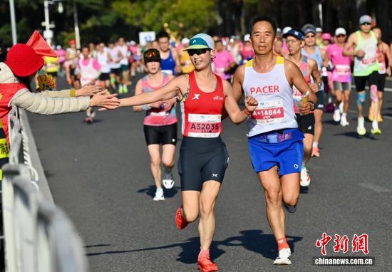 图为选手与赛道旁的加油观众击掌。中新社记者 王东明 摄 图为选手与赛道旁的加油观众击掌。中新社记者 王东明 摄