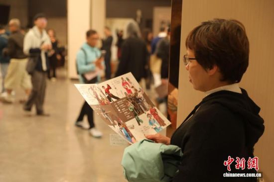 1月15日晚,一名台湾观众在等待入场时翻看戏曲表演介绍。中新社记者 刘大炜 摄 1月15日晚,一名台湾观众在等待入场时翻看戏曲表演介绍。中新社记者 刘大炜 摄