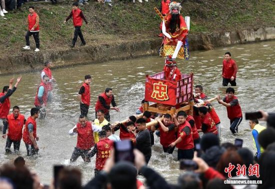 图为村民们抬着“古事”在水中逆行。中新社记者 张斌 摄 图为村民们抬着“古事”在水中逆行。中新社记者 张斌 摄