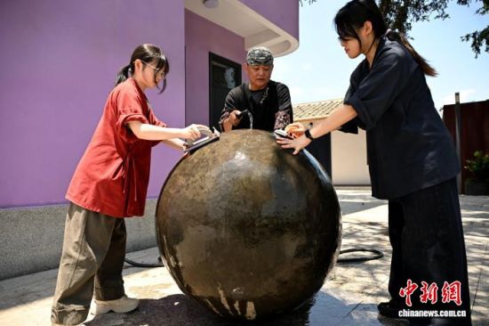 5月19日,在福建省福州市罗源县起步镇桂林村的闽台非遗文创交流空间里,黄守堃与徒弟曾惠婷(左)、葛守汐(右)为目前正在创作的大型脱胎漆器装置进行水打磨。中新社记者 吕明 摄 5月19日,在福建省福州市罗源县起步镇桂林村的闽台非遗文创交流空间里,黄守堃与徒弟曾惠婷(左)、葛守汐(右)为目前正在创作的大型脱胎漆器装置进行水打磨。中新社记者 吕明 摄