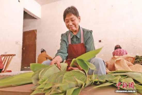 图为工人仔细挑选箬叶。陈玉婕摄 图为工人仔细挑选箬叶。陈玉婕摄