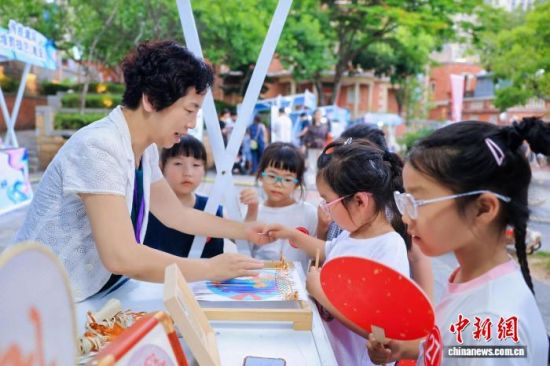 6月13日,国家级非物质文化遗产代表性项目永春纸织画代表性传承人方碧双(左)在非遗市集向小朋友展示纸织画文创产品。 中新社记者 孙虹 摄 6月13日,国家级非物质文化遗产代表性项目永春纸织画代表性传承人方碧双(左)在非遗市集向小朋友展示纸织画文创产品。 中新社记者 孙虹 摄