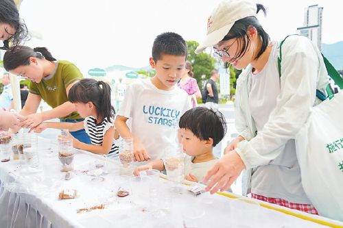 家长陪孩子玩环保小游戏。本报记者 包华摄 家长陪孩子玩环保小游戏。本报记者 包华摄