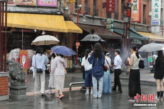 8月19日,位于大稻埕的台北霞海城隍庙香火氤氲,冒雨前来的年轻身影络绎不绝。 中新社记者 朱贺 摄 8月19日,位于大稻埕的台北霞海城隍庙香火氤氲,冒雨前来的年轻身影络绎不绝。 中新社记者 朱贺 摄