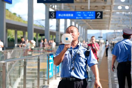 盛廷飞正在提示旅客抓紧时间上车。黄凌杰 摄 盛廷飞正在提示旅客抓紧时间上车。黄凌杰 摄