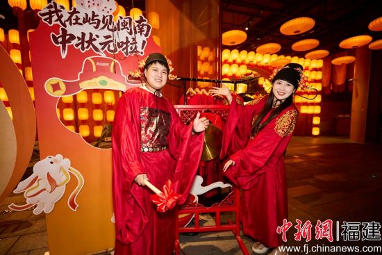 图为游客在“屿见闽南”景区体验厦门特色民俗博饼,博得状元的游客穿上状元服、敲响状元锣。(厦门“屿见闽南” 供图) 图为游客在“屿见闽南”景区体验厦门特色民俗博饼,博得状元的游客穿上状元服、敲响状元锣。(厦门“屿见闽南” 供图)