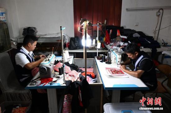 10月9日,位于福建省福州市罗源县的福州市畲族服饰传习所里,缝纫机的“哒哒”声响个不停,兰银才(左)与父亲兰曲钗正在制作畲族服饰。 中新社记者 吕明 摄 10月9日,位于福建省福州市罗源县的福州市畲族服饰传习所里,缝纫机的“哒哒”声响个不停,兰银才(左)与父亲兰曲钗正在制作畲族服饰。 中新社记者 吕明 摄